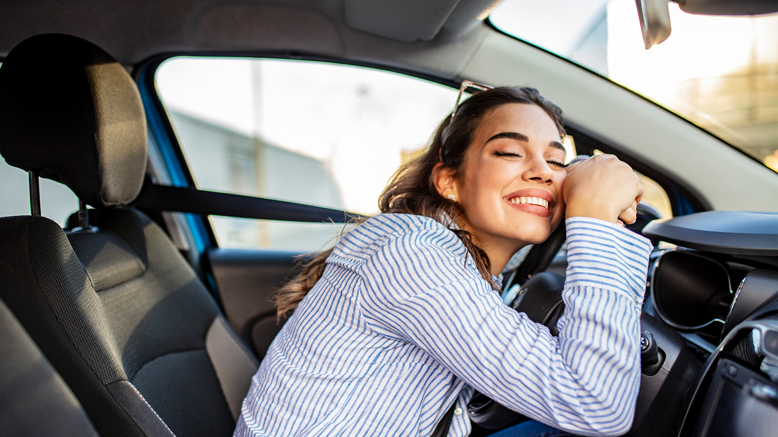Happy Woman Hugging A Sterring Wheel Inside A Car